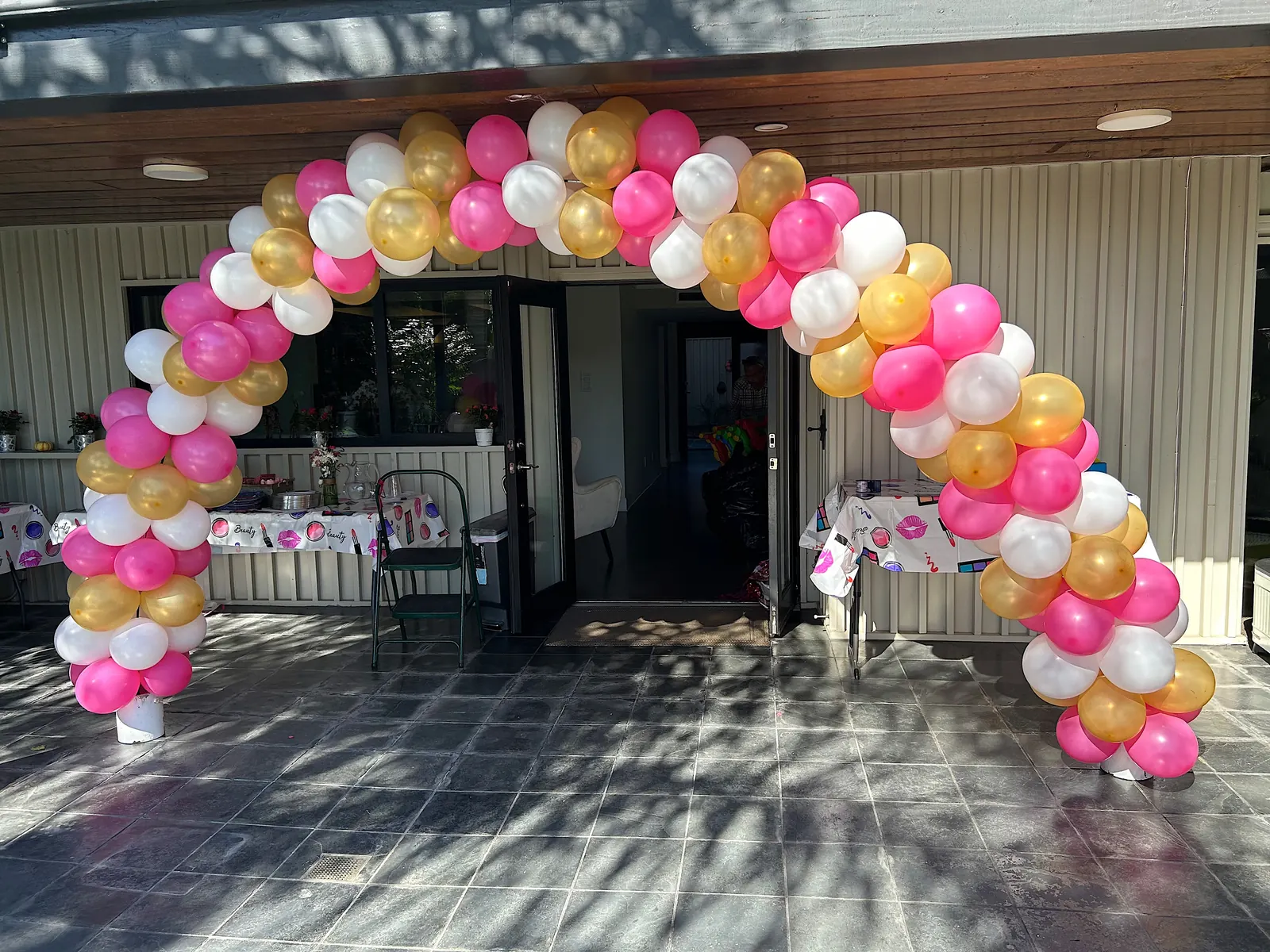 Pink, gold and white balloon arch over a patio entrance in Los Angeles