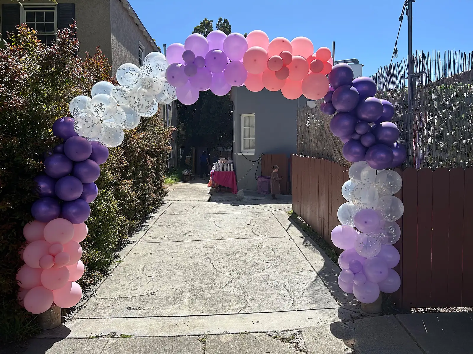 Purple, pink and silver confetti balloon arch over a walkway