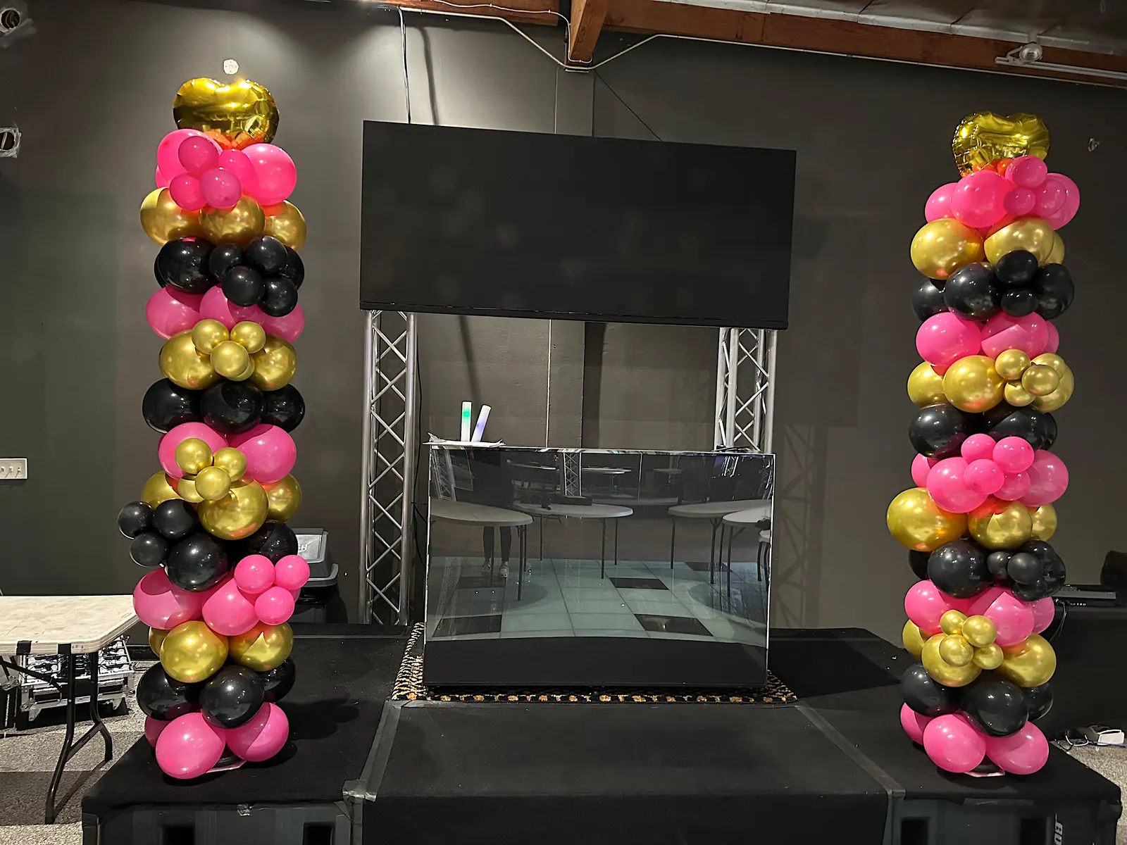 Pair of hot pink, black and gold balloon columns on a stage