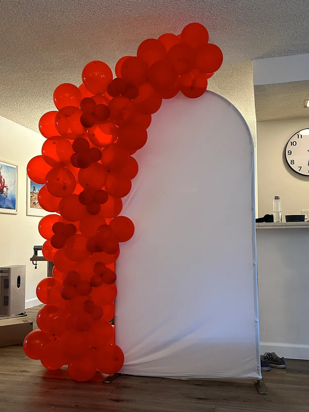 Arched white Chiara backdrop with a red organic balloon garland